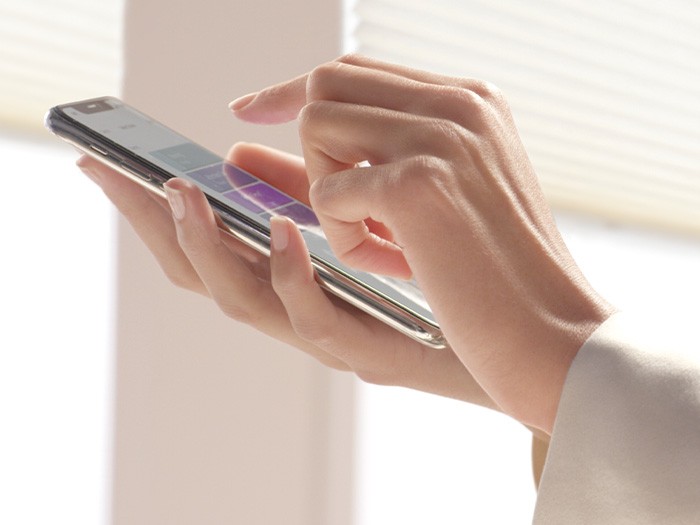 A person operating a smartphone to control the window treatments from an app, with PowerView® Automation.